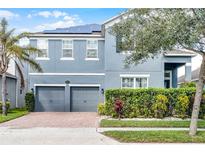 Two-story home featuring a two-car garage, solar panels, well-maintained landscaping, and a charming blue facade at 15373 Murcott Harvest Loop, Winter Garden, FL 34787