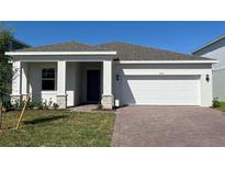 Charming single-story home with a brick driveway and two-car garage, set against a bright blue sky at 2051 Town Pasture Dr, Eustis, FL 32726