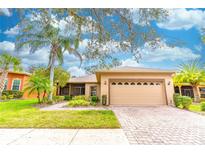 Charming one-story home featuring a manicured lawn, brick driveway, and a two-car garage at 321 Davinci Pass, Kissimmee, FL 34759