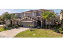 Beautiful two-story home features a well-manicured lawn, mature palms, a tile roof, and a two-car garage at 5251 Wildwood Way, Davenport, FL 33837
