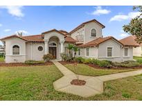 Stunning two-story home featuring a terracotta tile roof, manicured lawn, and lush landscaping at 10616 Emerald Chase Dr, Orlando, FL 32836