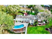 Expansive property featuring a pool with a deck, lush greenery, and a charming, light-colored two-story home at 1400 Tedford St, Eustis, FL 32726