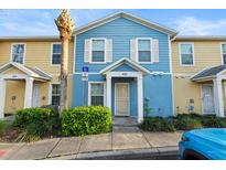 Charming two-story townhouse with blue and yellow exterior and well-maintained landscaping at 2478 Pillar Coral Dr # S, Orlando, FL 32808