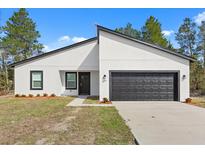 Newly built home featuring white exterior with a modern black-trimmed garage and windows at 3995 Sw 151 Street, Ocala, FL 34473