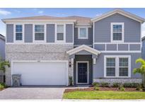 Charming two-story home with a stone facade, manicured lawn, and a two-car garage, creating an inviting curb appeal at 4149 Lana Ave, Davenport, FL 33897
