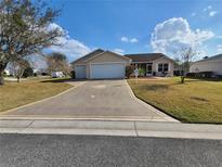 Charming single-story home with a well-manicured lawn and a spacious three car driveway at 1380 Red Ash Pl, The Villages, FL 32162