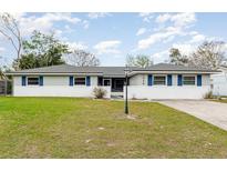 Charming single-story home featuring a well-manicured lawn, blue shutters, and a brick facade at 1038 E Hancock Dr, Deltona, FL 32725