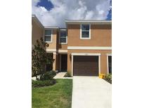 Two-story townhome with an attached single car garage and a well-manicured front lawn and landscaping at 1560 Chelsea Dr, Davenport, FL 33897