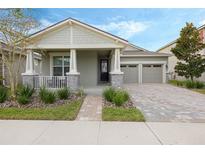 Charming single-Gathering home featuring a covered front porch, brick driveway, and a two-car garage at 16410 Taliesin St, Winter Garden, FL 34787