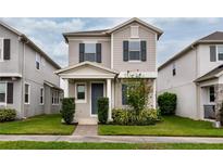 Charming two-story home featuring a well-manicured lawn, a gray facade, and a welcoming front porch at 210 Wooded Vine Dr, Winter Springs, FL 32708