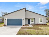 Modern one-story home showcasing a blue garage door and complementary blue front door at 4016 Sw 151 Street, Ocala, FL 34473