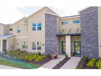 Attractive two-story townhome featuring stone accents, green door, and well-manicured landscaping at 432 Ocean Course Ave, Davenport, FL 33896