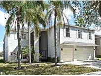 Two-story home with an attached two-car garage, pale blue paint, white trim, and lush palm trees at 1215 Castleport Rd, Winter Garden, FL 34787