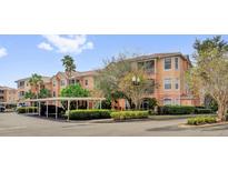 Exterior of a peach colored condo building with private balconies and covered parking at 13500 Turtle Marsh Loop # 816, Orlando, FL 32837