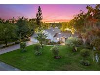 Stunning home featuring lush landscaping, mature trees, and a charming brick driveway at sunset at 1374 Cor Jesu Ct, Longwood, FL 32750