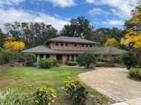 Charming two-story home with a well-manicured lawn, mature trees, and a circular brick driveway at 1606 The Oaks Dr, Maitland, FL 32751