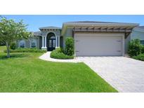 Charming single-story home with a manicured lawn, a pergola over the garage, and a double door entrance at 202 Stargrass Dr, Auburndale, FL 33823