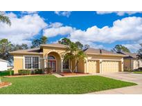 Charming one-story home featuring a three-car garage, lush lawn, and vibrant red front door, beneath a bright, cloudy sky at 2582 Greenwillow Dr, Orlando, FL 32825