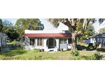 Charming single-story home with a vibrant red roof and a well-maintained front yard with mature landscaping at 963 26Th Nw St, Winter Haven, FL 33881