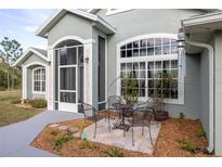 Charming home exterior with large windows, screened entrance and outside seating at 1045 S State Road 415, New Smyrna Beach, FL 32168