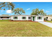 Charming single-story home featuring a well-maintained lawn, crisp white exterior, and colorful landscaping at 1612 Idaho Ave, Belle Isle, FL 32809