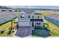 Charming two-story home with gray siding, manicured lawn, and brick paved driveway at 1795 Nw 44Th Ct Rd, Ocala, FL 34482