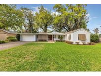 Charming single-story home with a lush green lawn and a brick-paved driveway at 5569 Jessamine Ln, Orlando, FL 32839