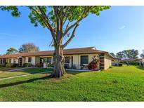 Charming home exterior with a well-manicured lawn, beautiful landscaping, and mature shade tree at 30113 Robin Ln, Tavares, FL 32778