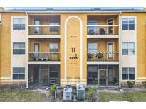 Exterior view of a three-story condo with balconies and screened in patios and AC units below at 5255 Images Cir # 305, Kissimmee, FL 34746