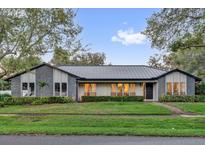 Charming single-story home with gray brick accents, manicured lawn, and lush landscaping at 7545 Lake Dr, Belle Isle, FL 32809