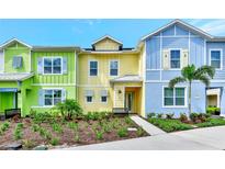 Charming colorful townhome showcasing a landscaped front yard with lush greenery and palm trees at 8146 Coconut Pl, Kissimmee, FL 34747