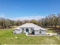 Charming home featuring a blue door, arched windows, and lush green lawn at 10688 Sw 129Th Terrace Rd, Dunnellon, FL 34432