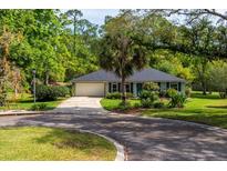 Charming single-story home with a well-manicured lawn, mature trees, and a winding driveway at 113 Wheatland Ct, Longwood, FL 32779
