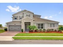 Charming two-story home featuring a stone accent entry, gray trim and siding, manicured lawn and well-kept landscaping at 16828 Sanctuary Dr, Winter Garden, FL 34787