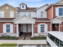 Charming townhouse exterior featuring red and tan siding, white trim, and well-maintained landscaping at 7558 Sunflower Cir, Kissimmee, FL 34747