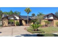 Charming single-story home with well-manicured lawn, mature palm trees, and solar panels on the roof at 872 Huckleberry Ln, Winter Springs, FL 32708