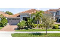 Charming single-story home with lush landscaping, a terracotta roof, and a two-car garage at 13319 Alderley Dr, Orlando, FL 32832