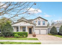 Charming two-story home with a manicured lawn, brick driveway, and a welcoming front porch with stone accents at 14150 Aldford Dr, Winter Garden, FL 34787