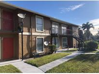 The apartment building features a brown exterior, red doors, and a staircase leading to the upper level units at 1909 Caralee Blvd # 4, Orlando, FL 32822