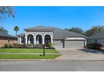 Charming single-story home with a well-manicured lawn, gray color palette, and a three car garage at 2732 Aloma Oaks Dr, Oviedo, FL 32765