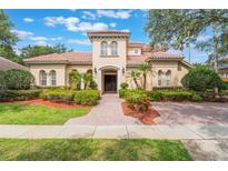 Stunning Mediterranean-style home featuring a red tile roof, lush landscaping, and a welcoming brick walkway at 8814 Southern Breeze Dr, Orlando, FL 32836