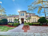 Stunning two-story home features a clay tile roof, lush landscaping, and a paver driveway at 8814 Southern Breeze Dr, Orlando, FL 32836