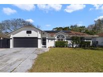 Charming single-story home featuring a black garage door, white siding, and manicured front lawn at 10562 Bridlewood Ave, Orlando, FL 32825