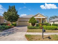 Charming single-story home with a two-car garage, beautiful landscaping, and a brick driveway at 117 Cupania Ct, Groveland, FL 34736