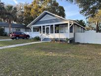 Charming bungalow with welcoming front porch, gray and white paint, and a well-maintained lawn at 1404 High St, Leesburg, FL 34748