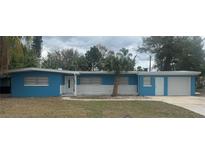 Charming single-story home with blue siding, white brick, a palm tree, and an attached one-car garage at 1907 Rockwell Rd, Orlando, FL 32808