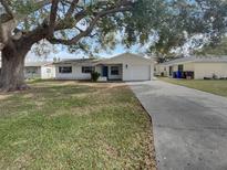 Charming single-story home with a lush green lawn, mature trees, and a long driveway leading to the garage at 437 Georgia Ave, St Cloud, FL 34769