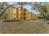 A yellow apartment building with balconies, and trees surrounding it at 5291 Images Cir # 302, Kissimmee, FL 34746