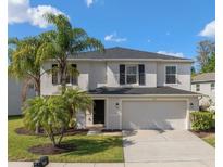 Charming two-story home featuring a two-car garage, well-maintained lawn and lush palm trees, creating a welcoming curb appeal at 12621 Oulton Cir, Orlando, FL 32832