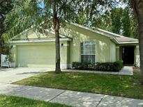 Charming one-story home featuring a well-maintained lawn, a two-car garage, and mature trees at 301 Sandy Ridge Dr, Davenport, FL 33896